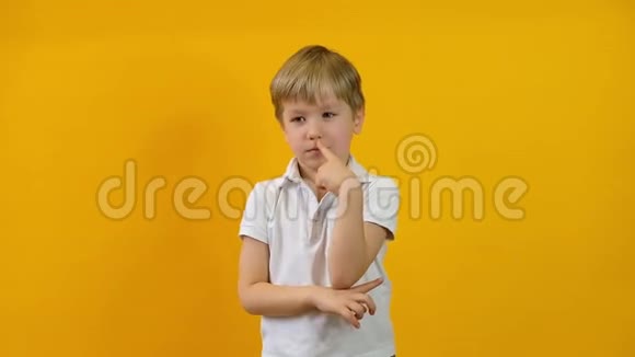 金发幼儿男孩思考和有一个想法孤立于黄色背景视频的预览图