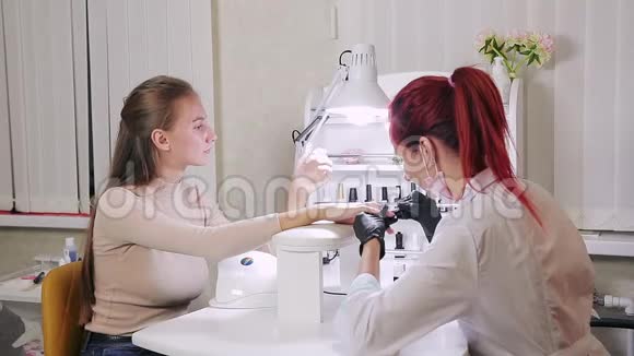 美容院的女美甲师在顾客的指甲上涂胶视频的预览图