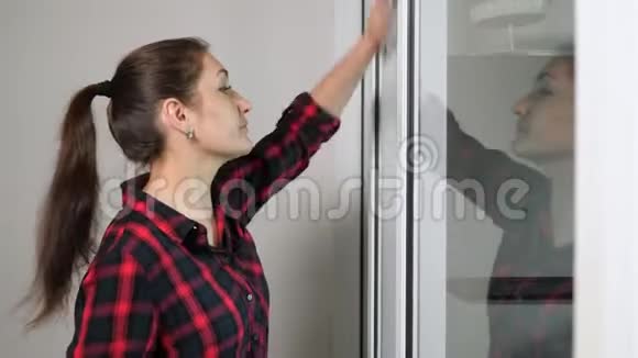 漂亮女孩用灰色抹布擦拭透明的门视频的预览图