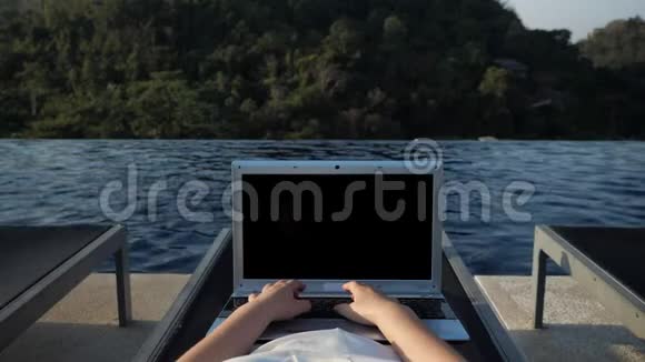 双手在泳池边休息女人的文字在笔记本电脑上靠山视频的预览图