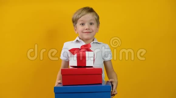 有趣的快乐小男孩蹒跚学步带着黄色背景的礼物微笑视频的预览图