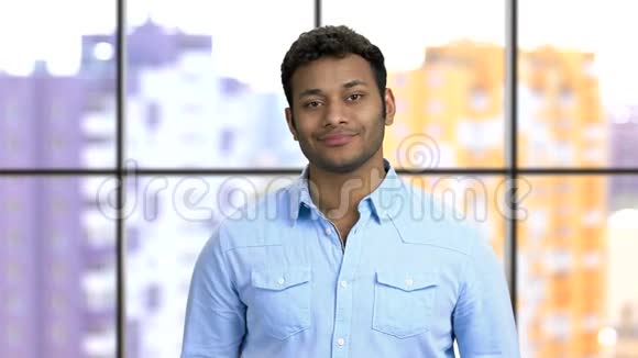 一个年轻快乐的深色皮肤男人穿着蓝色正式衬衫的肖像视频的预览图