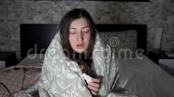 女人坐在床上毯子打喷嚏视频的预览图