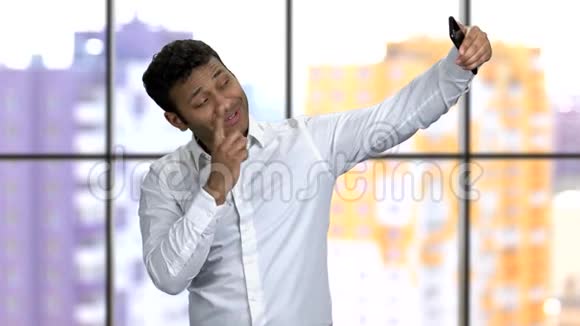 深色皮肤的男人穿着正式的衬衫在他的智能手机上的姿势视频的预览图