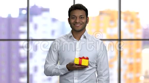 年轻开朗的棕色皮肤男人右手拿着礼品盒视频的预览图