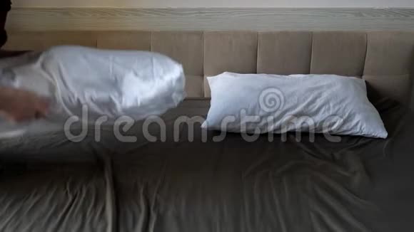 女士双手拍打着白色的枕头扔在棕色的大床上视频的预览图