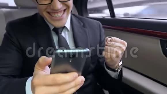 快乐的商人使用智能手机微笑着在汽车上表现出是的姿态视频的预览图