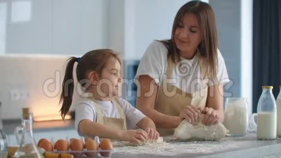 妈妈教女儿慢慢地在厨房里揉面包做饼干妈妈教小女儿学视频的预览图