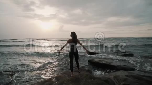 女孩站在石头上享受太阳落山的乐趣视频的预览图