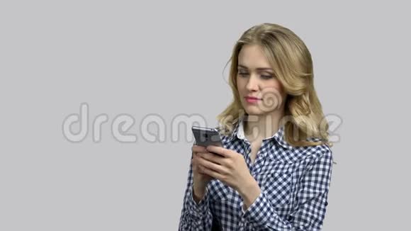 年轻的金发女人在她的智能手机上打字视频的预览图