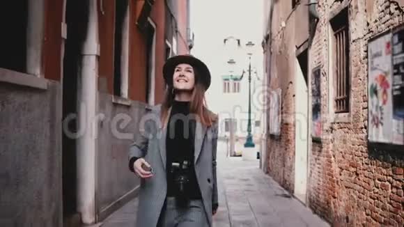 意大利威尼斯美丽的老街上带着相机微笑的迷人的快乐的职业女摄影师视频的预览图