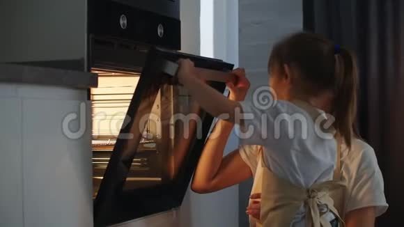 一个小女孩在厨房帮她妈妈关上烤箱门妈妈幼儿园助理快乐的孩子视频的预览图