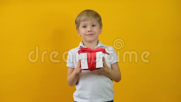 可爱快乐的小男孩蹒跚学步带着黄色背景的礼物微笑视频的预览图