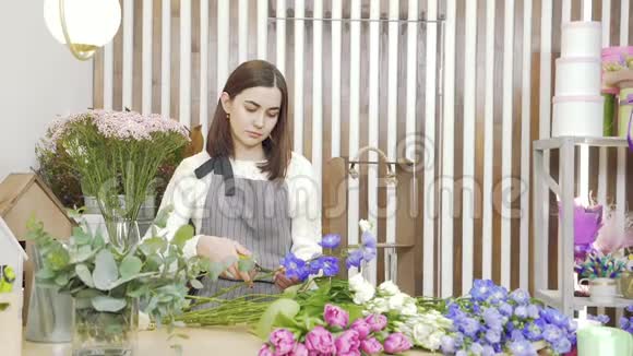年轻女子花店为制作花束或构图准备鲜花在车间检查和修剪视频的预览图