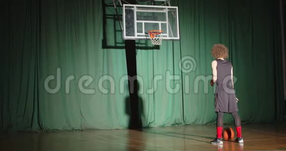 卷曲的篮球运动员看着篮筐抱着球准备自信独自阴影明亮的光束打绿色视频的预览图