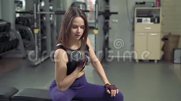 漂亮的健身女孩在健身房用哑铃练习运动运动俱乐部的年轻女子举重视频的预览图