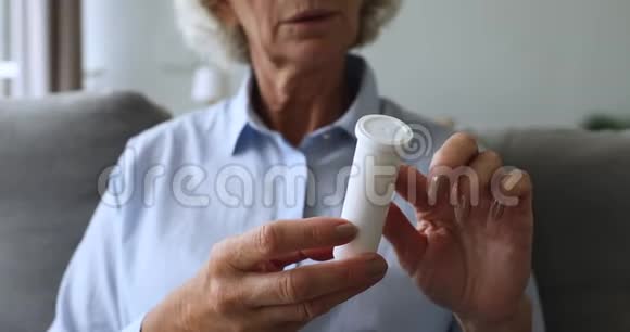 合上中年妇女拿着塑料瓶和药丸视频的预览图