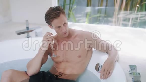帅哥坐在现代浴缸里喝香槟视频的预览图