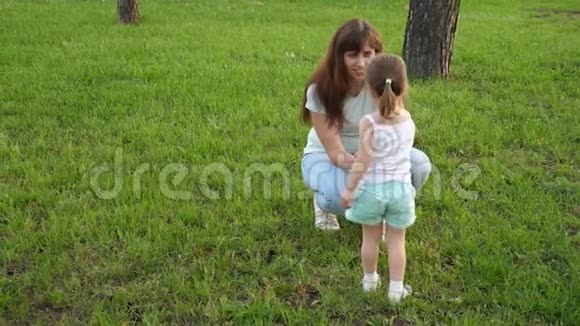 妈妈给她的孩子看松果小女儿和妈妈在草坪上公园里玩耍收集圆锥花序小孩走路视频的预览图
