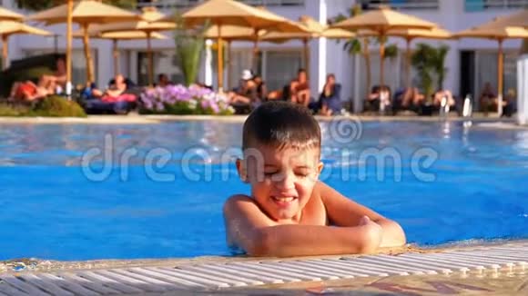 快乐的孩子在酒店的一个有蓝色水的游泳池里游泳慢动作视频的预览图