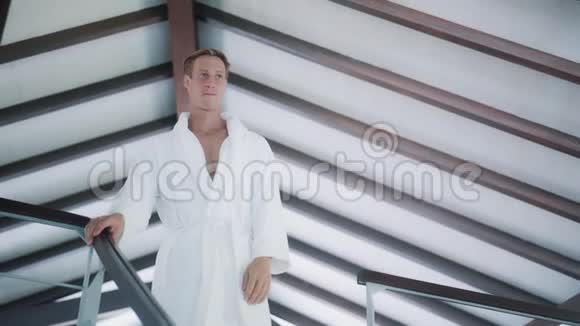 穿着白色浴袍的帅哥在房子里下楼视频的预览图