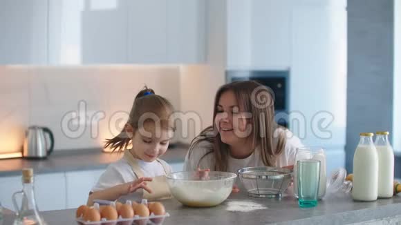 妈妈和女儿在厨房里放纵自己玩恶作剧女儿用面粉涂抹妈妈鼻子笑了视频的预览图