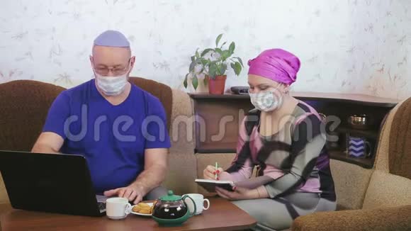 冠状病毒隔离的犹太蒙面夫妇在家远程工作视频的预览图