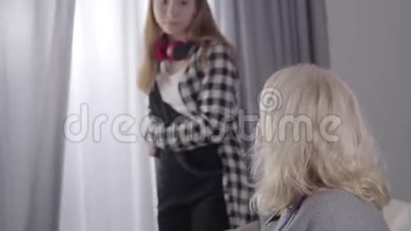 女性白人青少年与祖母争吵的肖像带着讽刺表情的女孩和金发女郎交谈视频的预览图