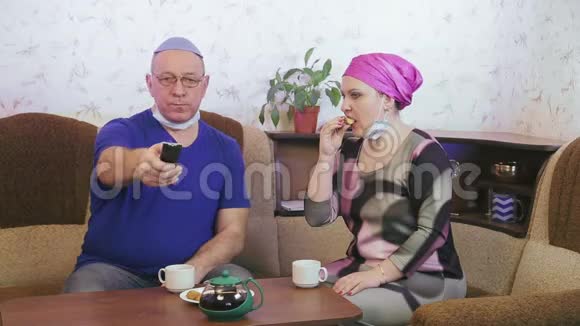 犹太已婚夫妇戴着防护面具在家中的沙发上喝酒以防止冠状病毒视频的预览图
