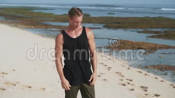 一个肌肉发达的人在河岸上脱掉黑色背心视频的预览图