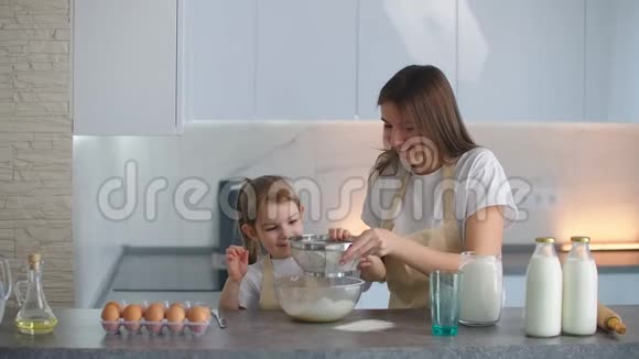 母女俩把面粉通过筛子撒到碗里妈妈教女儿揉面团重点关注视频的预览图