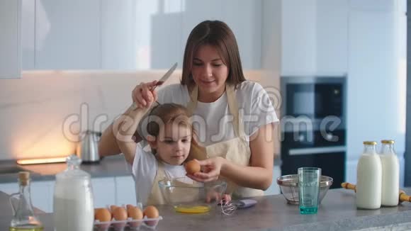 女人和女孩在厨房里扔鸡蛋女儿和母亲一起做饭视频的预览图