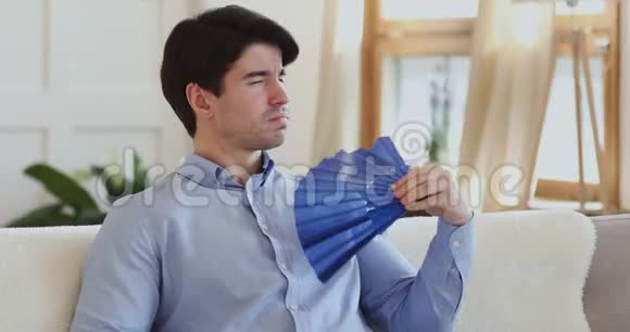 一个疲惫的男人在公寓里挥舞着扇子视频的预览图