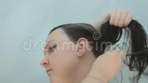 一个深色的女人用刷子染她的长发并梳头视频的预览图