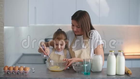 一个微笑的母亲帮助她的女儿学习如何做馅饼教一个小女孩回家帮忙视频的预览图