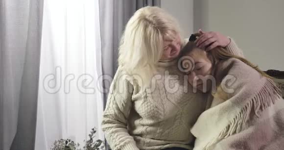 白人老妇人拥抱生病的女孩并给她橙色的肖像奶奶照顾生病的孙女视频的预览图