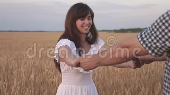 情侣男女牵着手在野外旅行跟我来一对年轻快乐的夫妇沿着金色的麦田奔跑视频的预览图