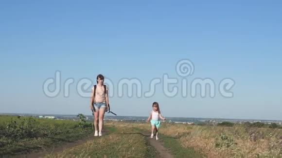 旅行者母亲带着一个孩子走在路上妈妈和小女儿出城旅行快乐的孩子沿着视频的预览图