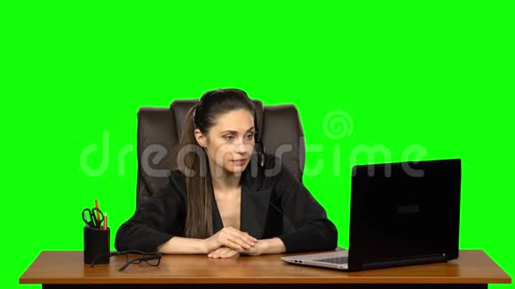 商务女性戴着耳机用网络摄像头说话看着笔记本电脑绿色屏幕视频的预览图