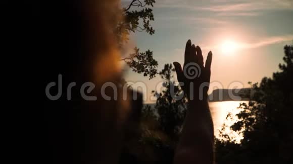 幸福的女孩在美丽的夕阳和大海的背景下举手慢动作在安定区射击视频的预览图