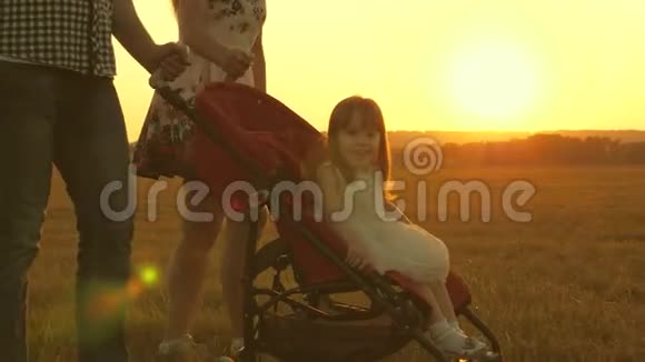 小女儿坐在公园里的婴儿车里在阳光的背景下童年和家庭概念带着一个小小的视频的预览图