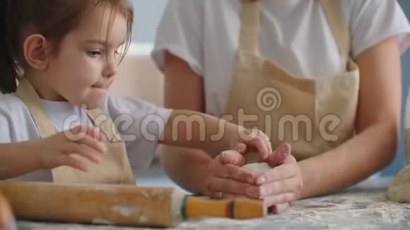 母亲和女儿在厨房用面团模具做饭母女俩抱着心形面团模具把它刻下来视频的预览图