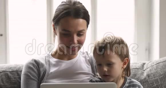 可爱的漂亮妈妈和孩子一起看有趣的卡通视频的预览图