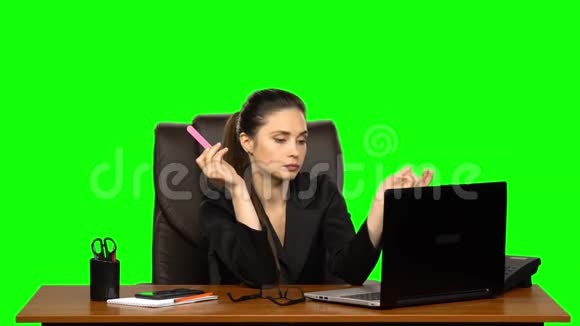 工作场所的女孩正在用笔记本电脑工作用两部手机说话锯钉子绿色屏幕视频的预览图