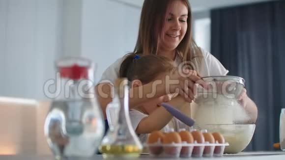 笑着妈妈和女儿一起用筛子把面粉筛进厨房视频的预览图