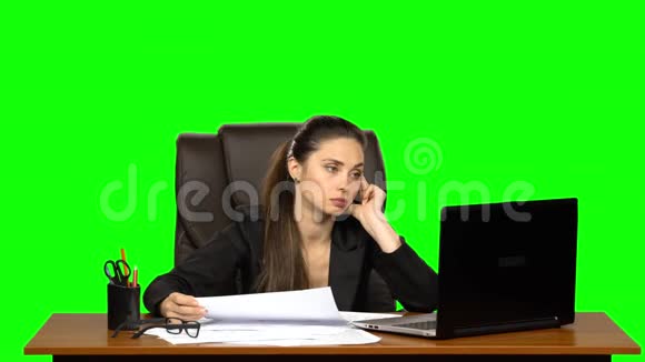 疲惫的女人读文件比较信息与笔记本电脑并揉皱纸绿色屏幕视频的预览图