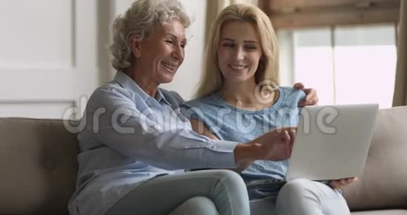 年长的中年妇女拥抱长大的女儿看照片视频的预览图