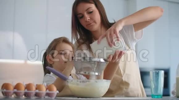 筛面粉家庭小生意的母亲一个糕点厨师一个面包师和一个年轻的助手一个女儿在一起视频的预览图