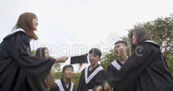 在大学校园里穿毕业礼服拿毕业证书的快乐学生视频的预览图