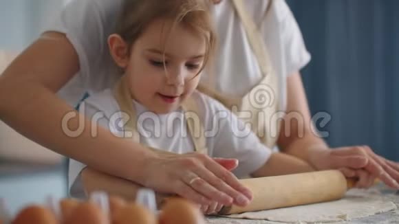 妈妈帮女儿滚面团妈妈和小女儿拿出面团做饼干使用滚针视频的预览图